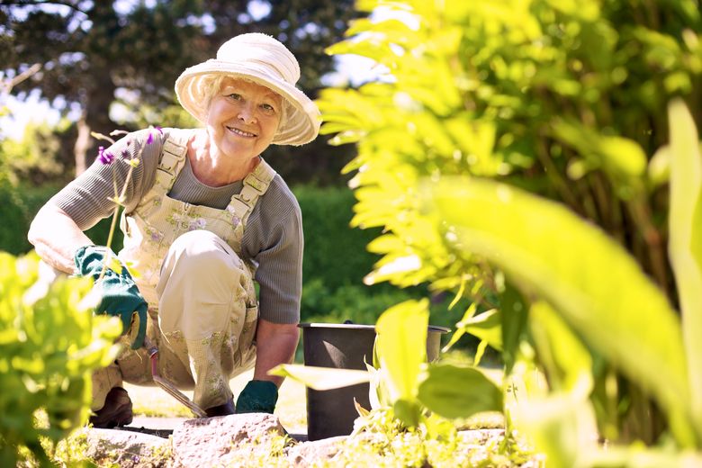 older gardener in her garden, smiling